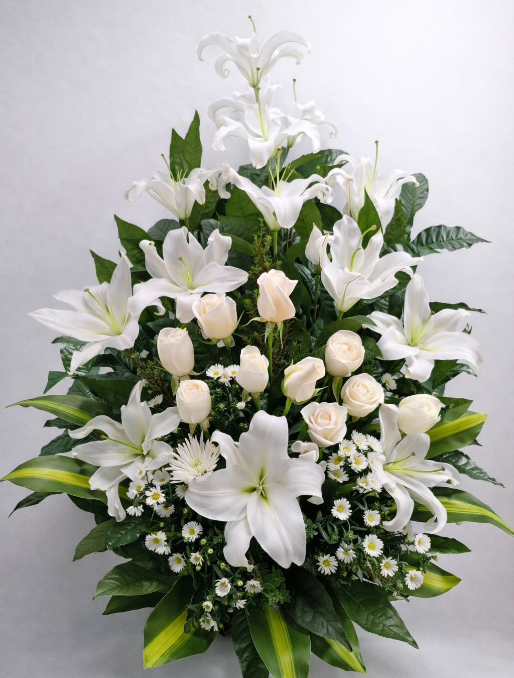 Consuelo Blanco – Arreglo fúnebre en cerámica de lirios blancos y rosas blancas con follaje bicolor