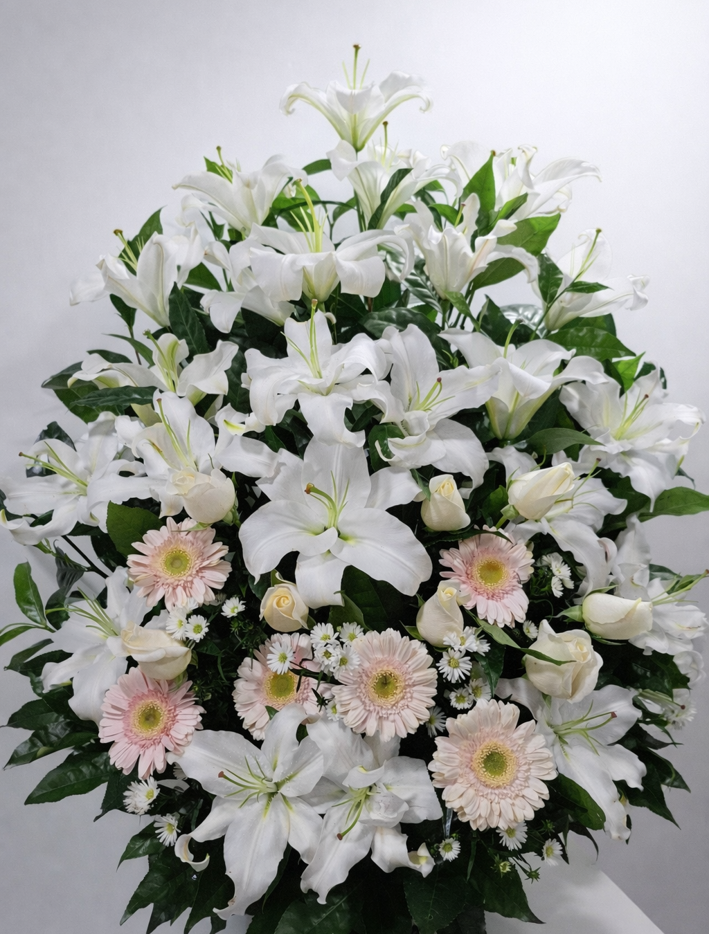 Bruma Rosada – Arreglo fúnebre en cerámica de lirios blancos, rosas blancas y gerberas rosa suave