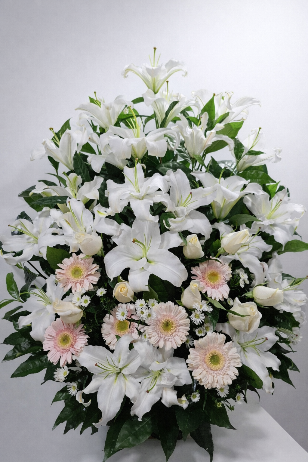 Bruma Rosada – Arreglo fúnebre en cerámica de lirios blancos, rosas blancas y gerberas rosa suave