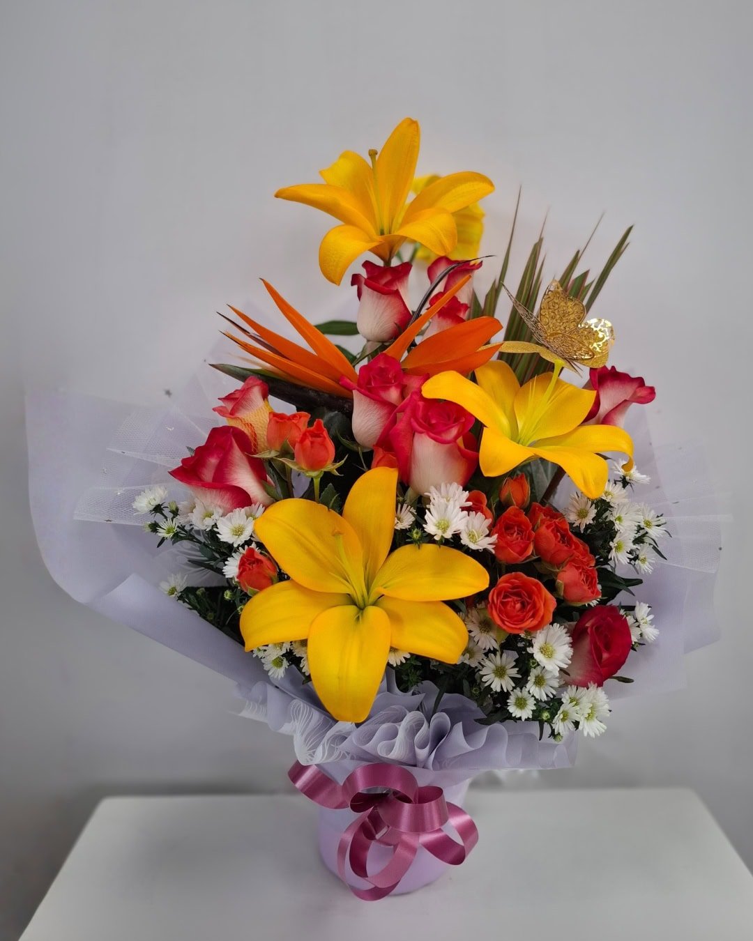 Amanecer Radiante – Arreglo en cerámica con lirios amarillos, rosas bicolor y mini rosas naranjas con toque exótico