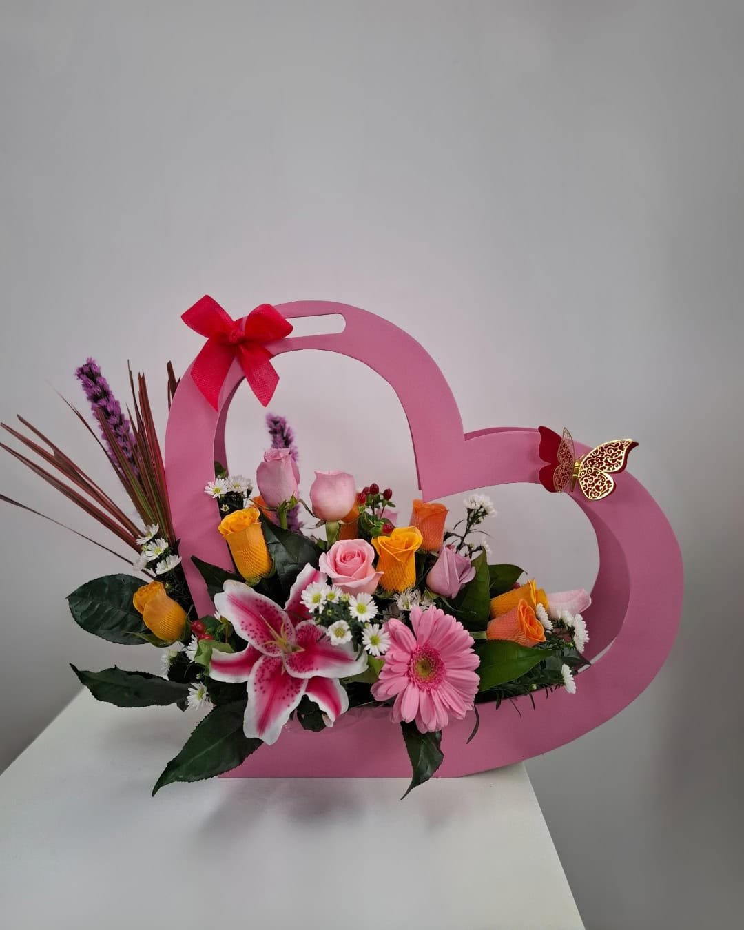 Lazo Dorado – Arreglo en base de madera (corazón) con Rosas bicolor y Lirio rosado, toque romántico