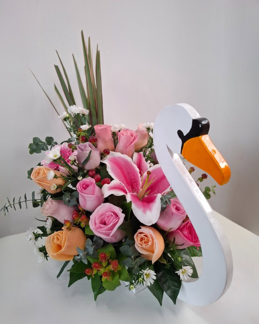 Cisne de Coral – Arreglo en base de madera (cisne) con Lirio rosado y Rosas pastel, detalle romántico