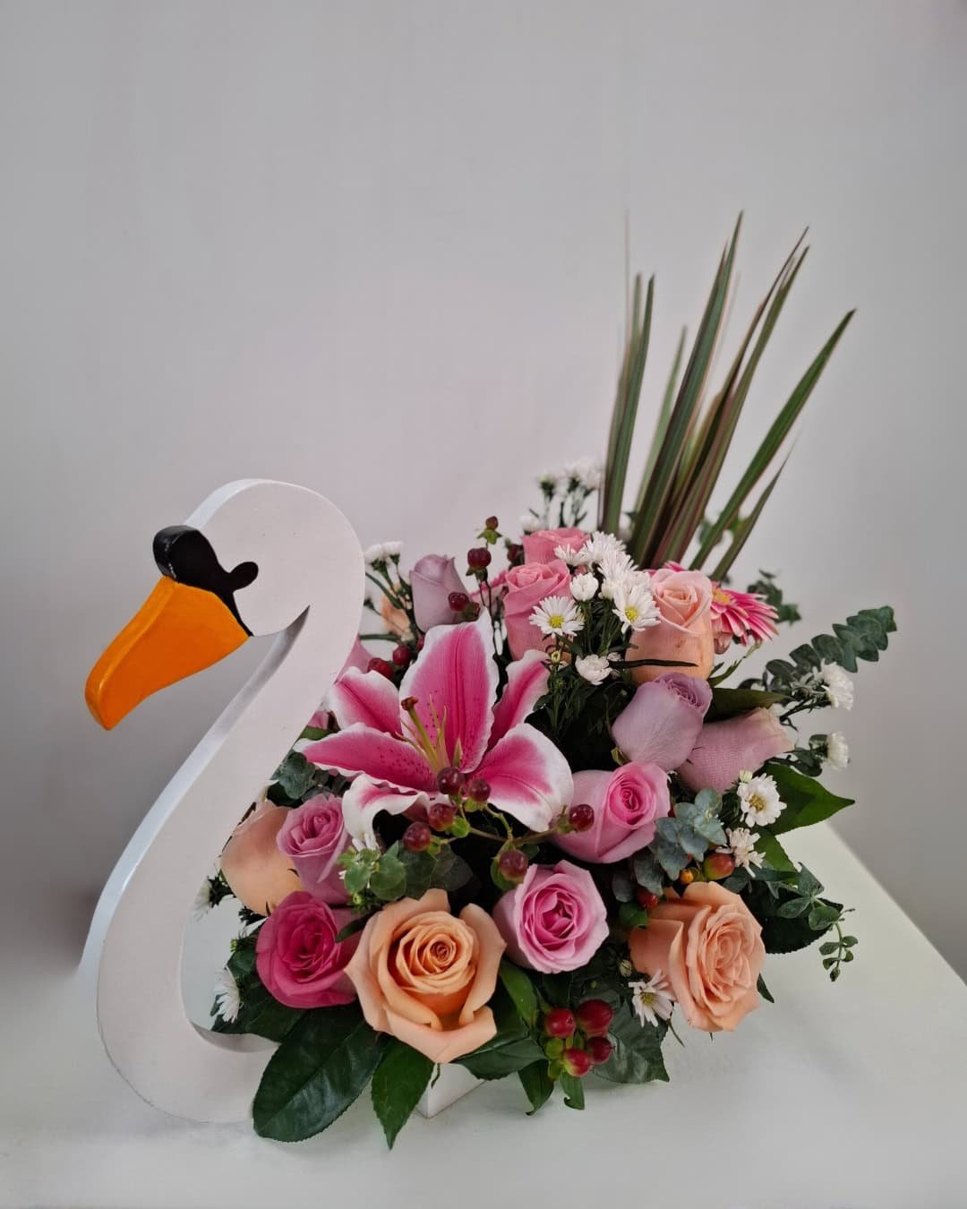 Cisne de Coral – Arreglo en base de madera (cisne) con Lirio rosado y Rosas pastel, detalle romántico