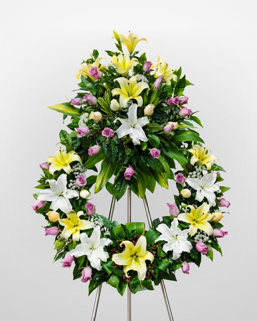 Serenidad – Corona Fúnebre en Trípode de Lirios Amarillos y Blancos con Rosas Lila, follaje premium