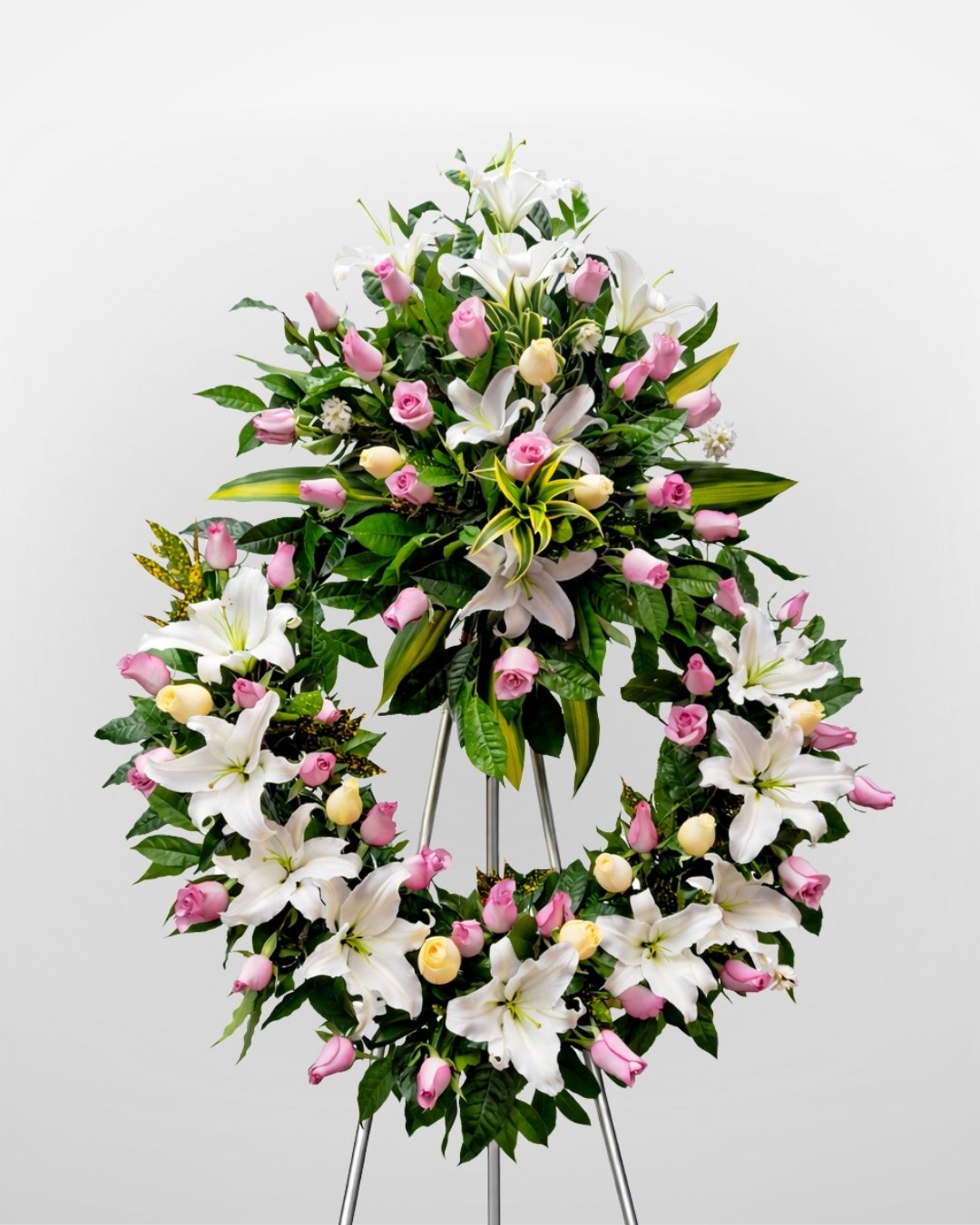 Aurora Rosé – Corona Fúnebre en Trípode de Rosas Rosadas con Lirios Blancos y Toque Delicado