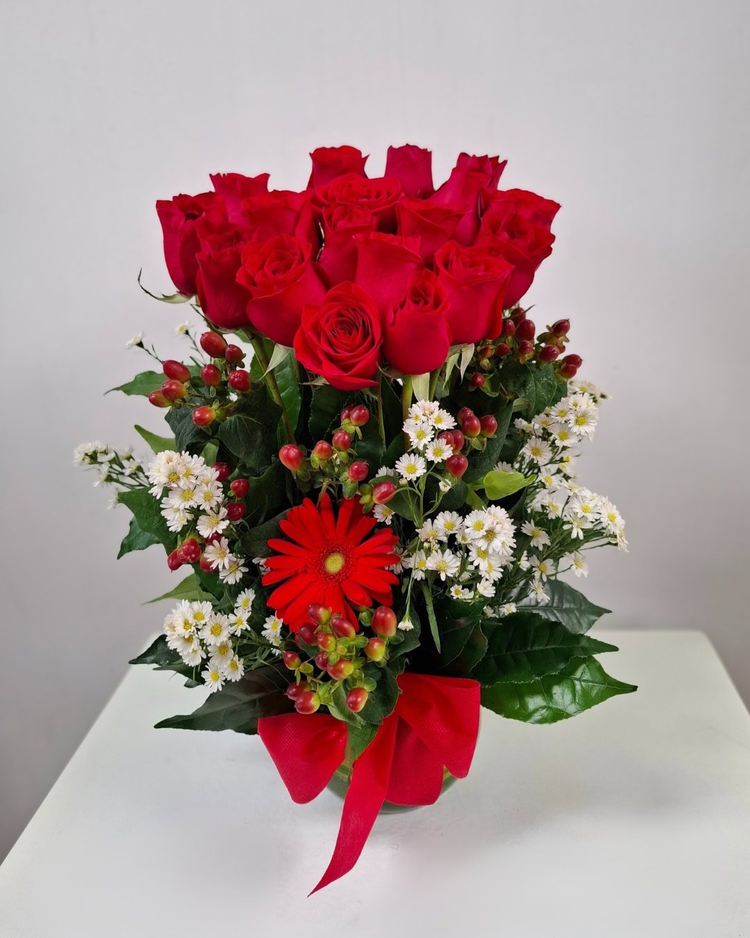 Carmesí – Florero pecera de rosas rojas con gerbera y bayas decorativas