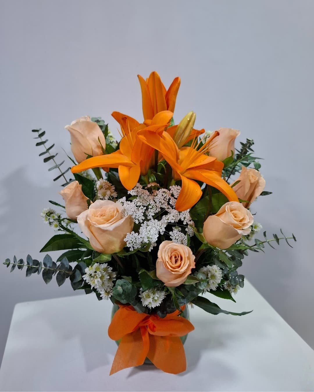 Ámbar – Florero pecera de lirios naranjas y rosas durazno con eucalipto