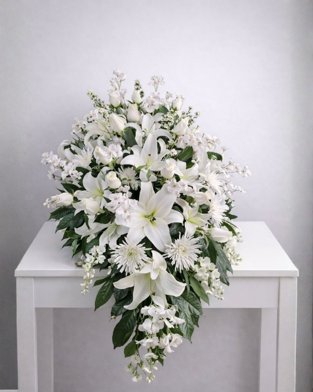 Velo de Luz – Lágrima Fúnebre de Lirios Blancos y Rosas Blancas con Flores de Nube y Follaje Premium