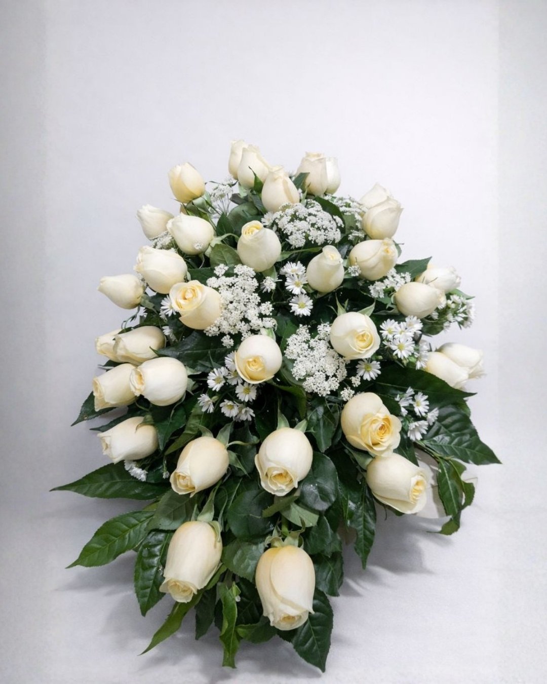 Paz Marfil – Lágrima fúnebre de rosas crema con follaje sobrio