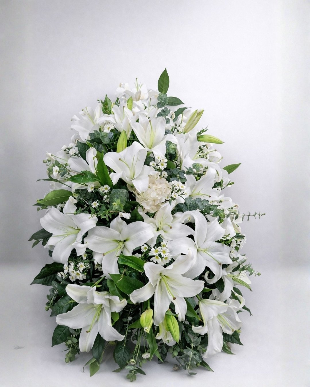 Blanca Serenidad – Lágrima fúnebre de lirios blancos con follaje premium