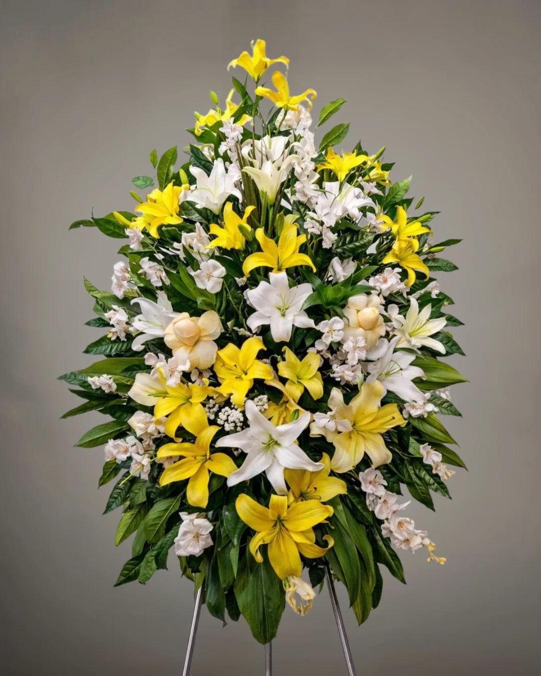 TRI-062 Aurora Dorada – Lágrima Fúnebre en Trípode de Lirios Amarillos y Blancos con Rosas Marfil y Follaje Abundante