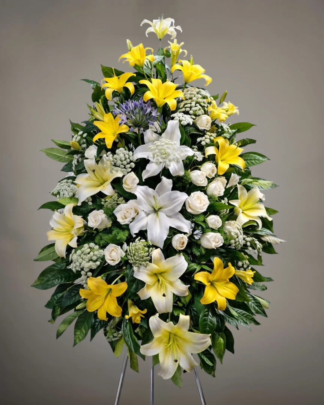 TRI-072 Sol de Paz – Lágrima Fúnebre en Trípode de Lirios Amarillos y Blancos con Rosas Marfil y Follaje Premium